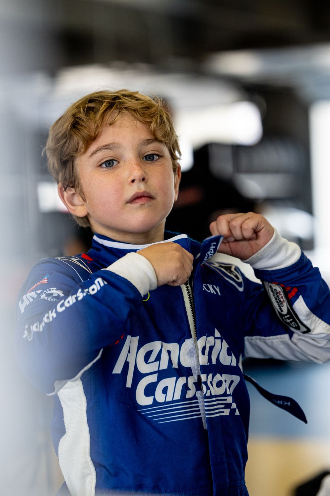 Kip zipping up his HendrickCars.com fire suit in the garage