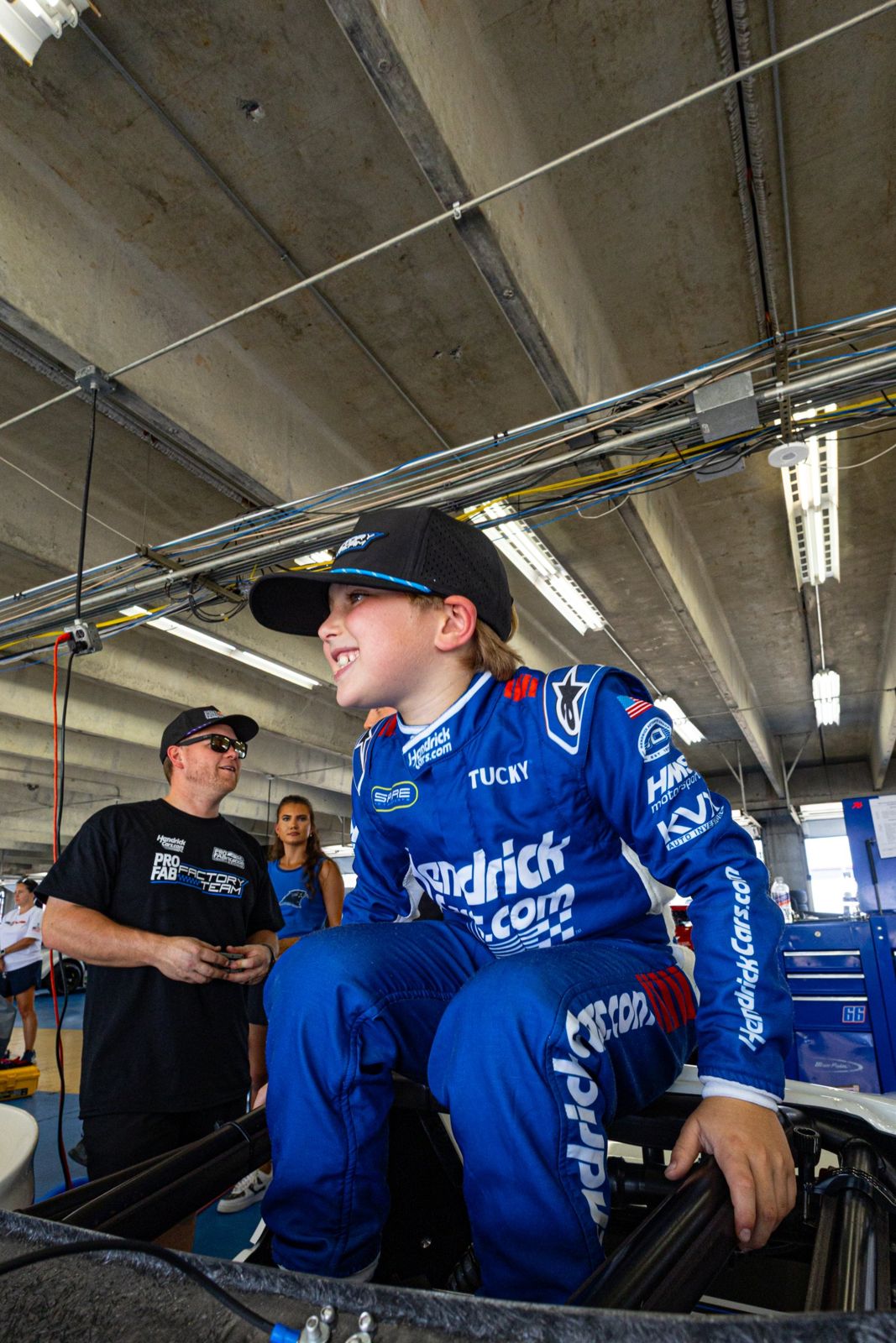 Kip in his blue HendrickCars.com fire suit, grinning as he climbs into his Bandolero