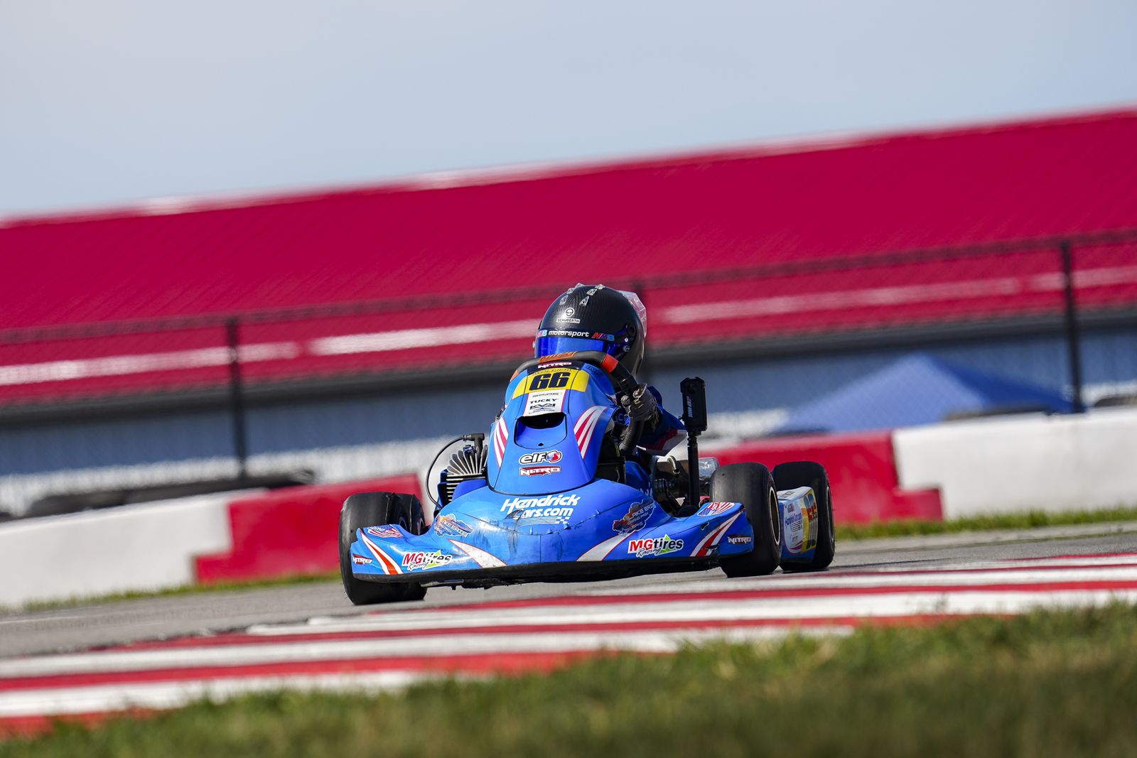 Kip's No. 66 kart heading down the straight past the red grandstands
