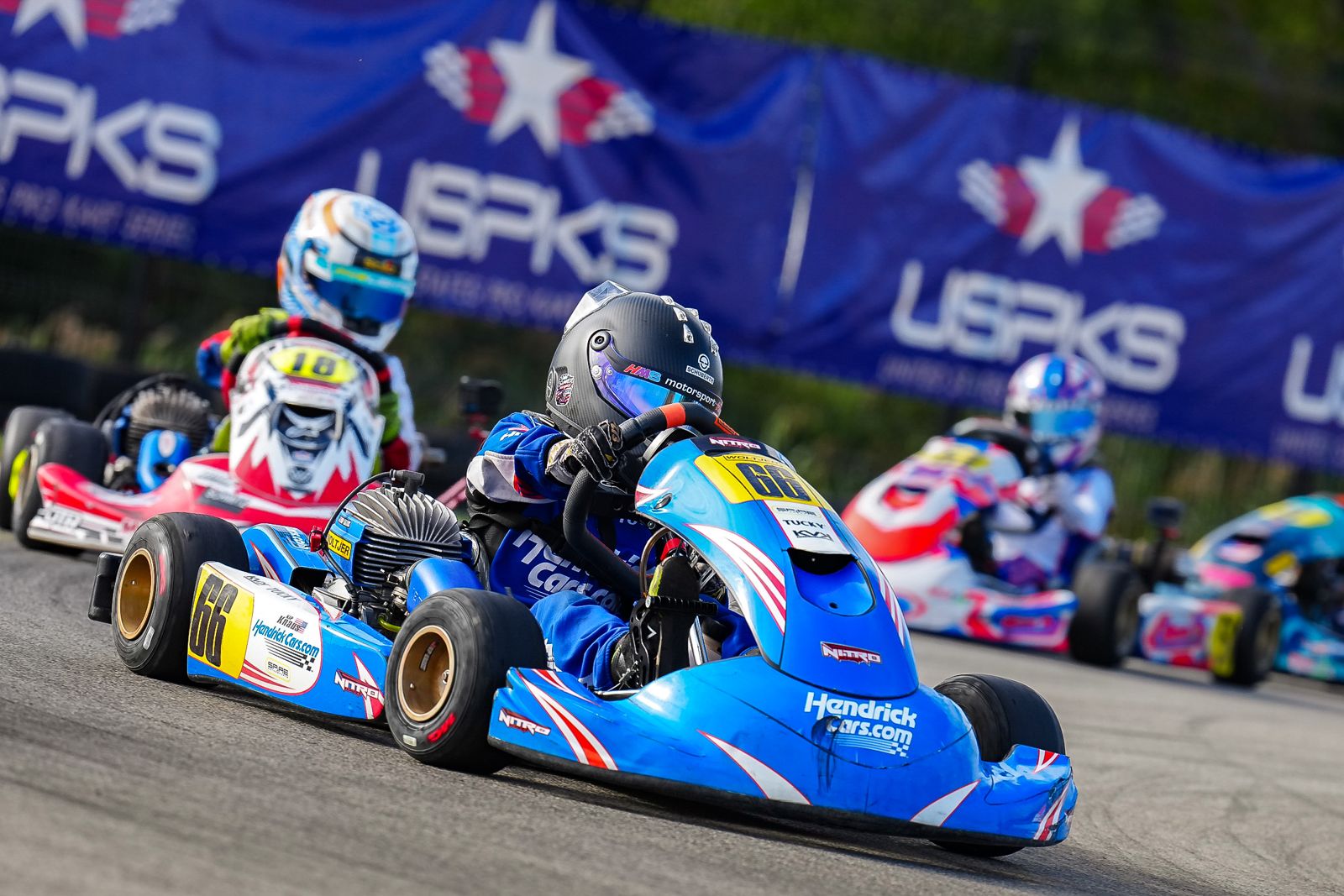 Kip in the No. 66 HendrickCars.com kart racing in front of the USPKS banners